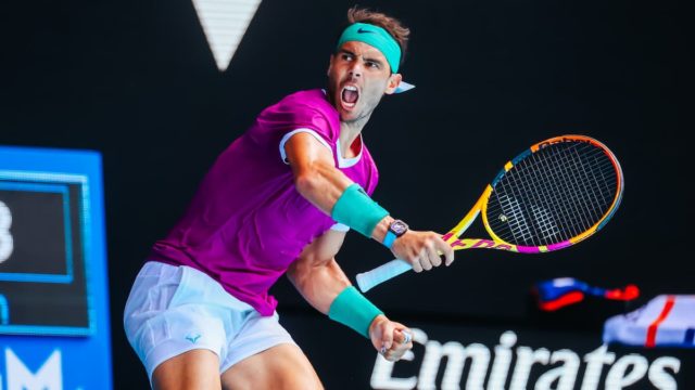 Rafael Nadal smiling while holding a trophy – reflecting his wealth and tennis success.