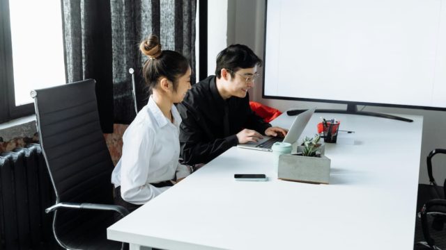 Woman Sitting Beside a Man In Front of a Laptop