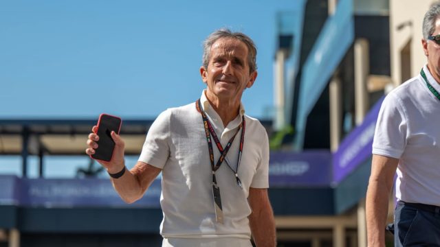 Alain Prost smiling in the F1 paddock with a trophy in hand, symbolising his success and net worth