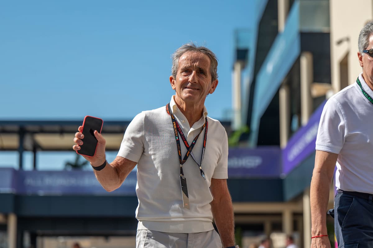 Alain Prost smiling in the F1 paddock with a trophy in hand, symbolising his success and net worth