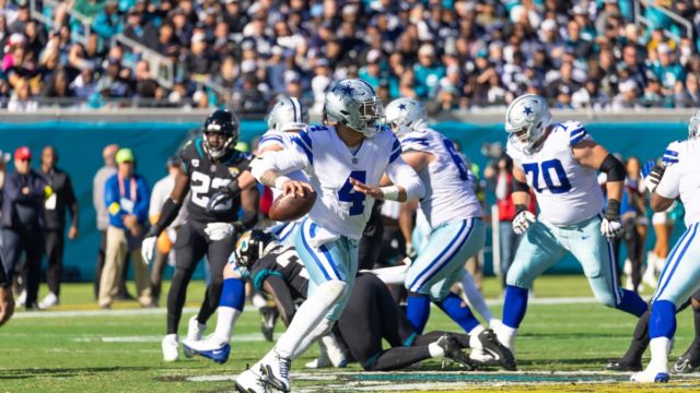 Dak Prescott smiling on the field in Dallas Cowboys gear