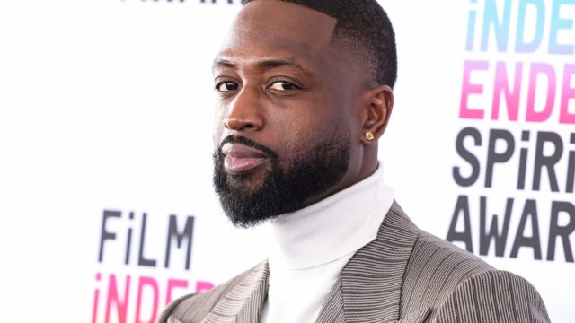 Dwyane Wade smiling in a luxury suit with background of Miami skyline representing his wealth