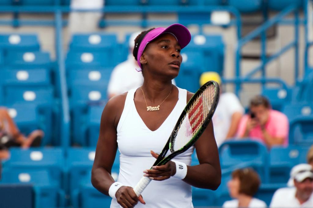 Venus Williams smiling at a tennis match, representing her successful career and wealth in 2025