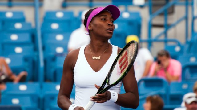 Venus Williams smiling at a tennis match, representing her successful career and wealth in 2025