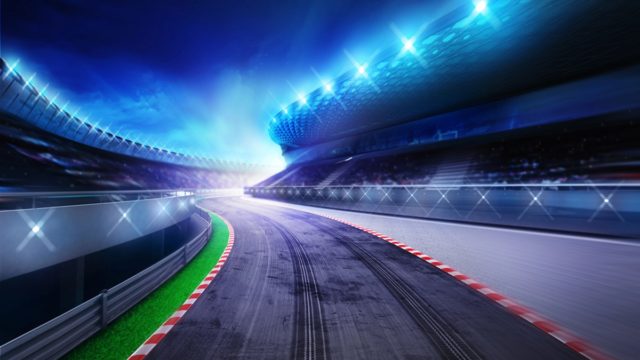 Overhead view of the full Formula 1 grid lined up on the start straight, representing modern F1 team budgets in the cost cap era