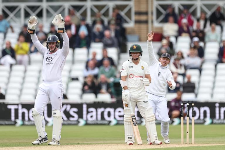 Cricket match showing batters, bowler, wicketkeeper and fielders during play