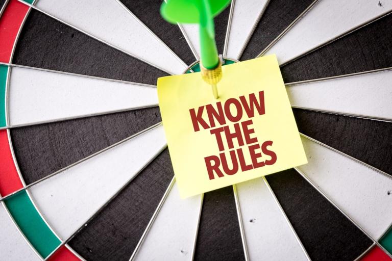 Professional darts player throwing on stage as darts rules are explained