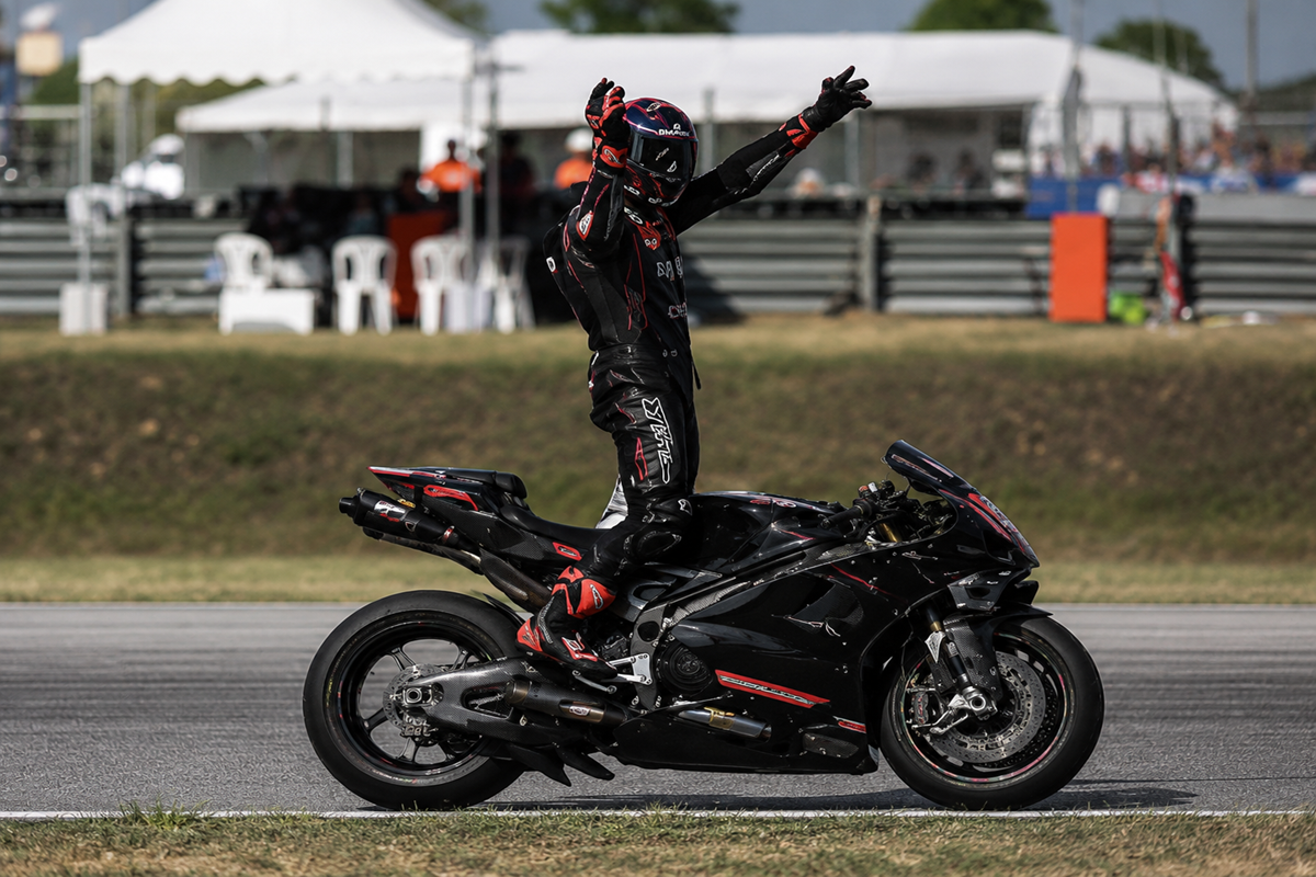 MotoGP rider celebrates on a black racing motorcycle during a victory lap on track